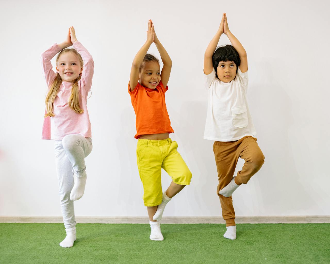 Three diverse children practicing yoga indoors, showcasing joy and balance.